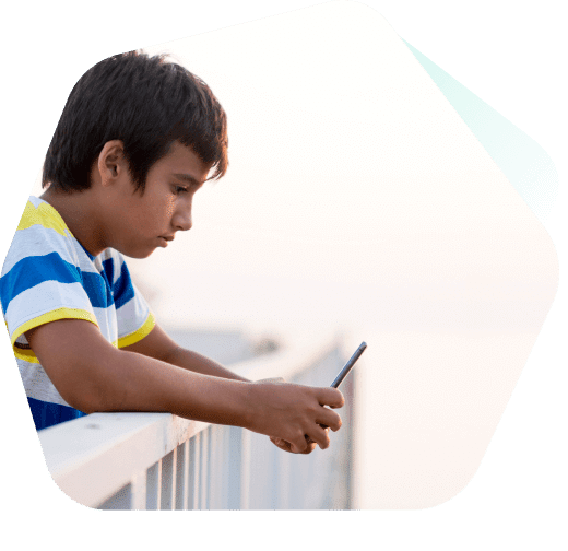 Jeune garçon assis à regarder des vidéos sur son téléphone portable