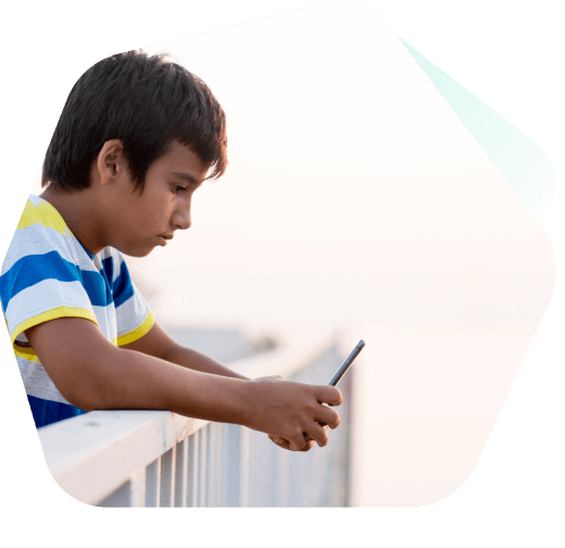 Jeune garçon assis à regarder des vidéos sur son téléphone portable